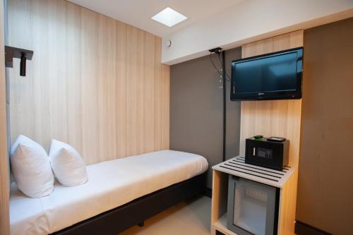 a small room with a bed and a tv at The Alfred Hotel in Amsterdam