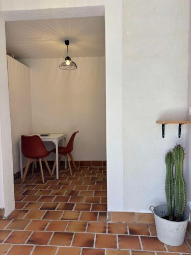 une salle à manger avec une table, des chaises et un cactus dans l'établissement Gîte - Douceur du Sud, entre mer et campagne, à Hyères