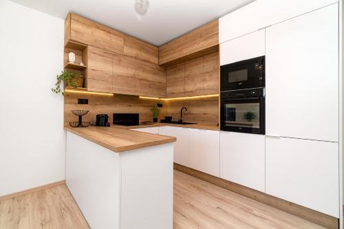 a kitchen with white cabinets and wooden walls at New BNB Apartment In the Ostrava with parking option in Slezská Ostrava