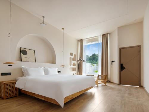 a bedroom with a large white bed and a large window at Leshan Summer Valley Mountain Stream in Leshan