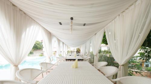 a white tent with white chairs and a table and a pool at Leshan Summer Valley Mountain Stream in Leshan