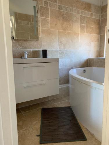 une salle de bain avec un lavabo, une baignoire et un miroir dans l'établissement Appartement en centre ville, à Corte