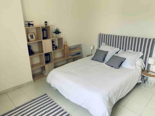 une chambre avec un grand lit blanc avec des oreillers dans l'établissement Appartement en centre ville, à Corte