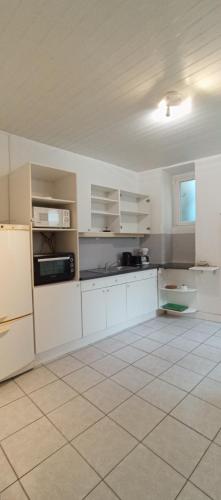 une cuisine avec des armoires blanches et un sol carrelé dans l'établissement Darmaillacq, à Cholet