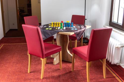 a table with red chairs and a chess board on it at Berggasthof Neues Haus in Kurort Oberwiesenthal