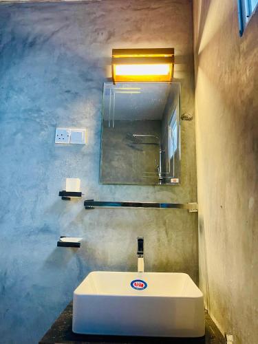 a bathroom with a white sink and a mirror at Warusha Villa in Hikkaduwa