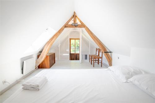 - une chambre mansardée avec un lit blanc et une salle à manger dans l'établissement Charmante maison semi-troglodyte, à Amboise