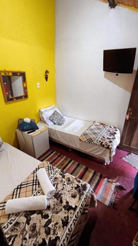 a room with two beds and a flat screen tv at Pousada Princesa da Serra in Serra do Cipo