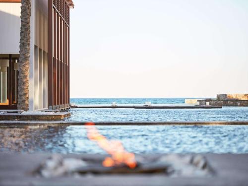 a person laying in a swimming pool next to the ocean at Amirandes, A Grecotel Resort to Live in Gouves