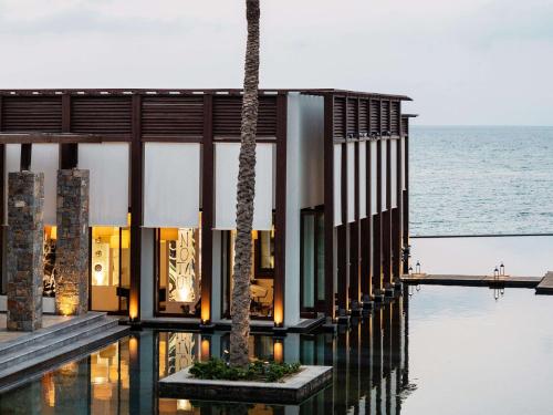 a house on the water with a palm tree at Amirandes, A Grecotel Resort to Live in Gouves