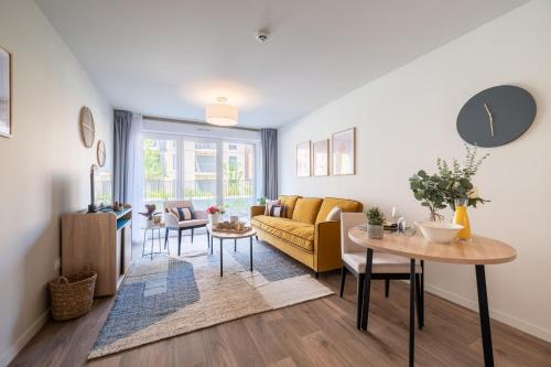 a living room with a yellow couch and a table at Zenao Appart'hôtels Villeneuve d'Ascq in Villeneuve d'Ascq