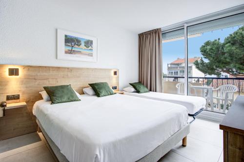 two beds in a hotel room with a balcony at Hotel Centre Plage in Argelès-sur-Mer