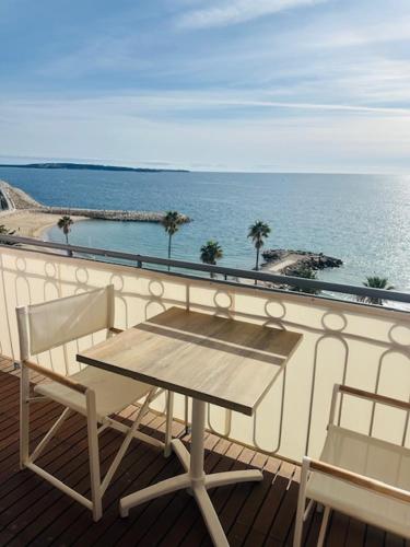 d'une table et de deux chaises sur un balcon donnant sur l'océan. dans l'établissement Appartement face mer proche palais, à Cannes