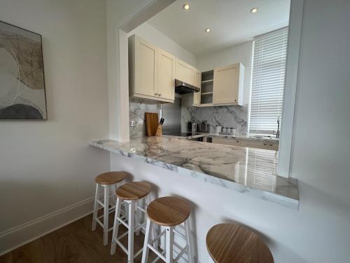 a kitchen with three bar stools and a counter at Hurstpier Spacious 2 Bed Apartment - by MCF in Hurstpierpoint