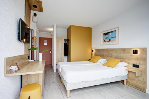 a bedroom with a bed and a desk and a television at Hotel Centre Plage in Argelès-sur-Mer