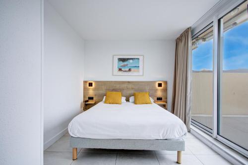 a bedroom with a white bed with yellow pillows at Hotel Centre Plage in Argelès-sur-Mer