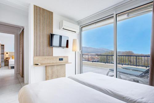 a bedroom with a bed and a balcony with a tv at Hotel Centre Plage in Argelès-sur-Mer