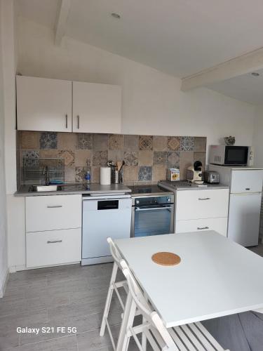 une cuisine avec des armoires blanches et une table blanche dans l'établissement L'oustalet, à Ceyreste