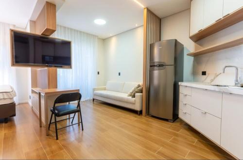 a kitchen with a refrigerator and a table and a couch at Kitnet Quarto Cozinha Sala Mobiliado in Piracicaba