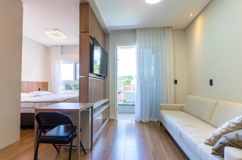 a living room with a couch and a desk and a bed at Kitnet Quarto Cozinha Sala Mobiliado in Piracicaba
