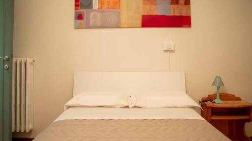 a white bed in a bedroom with a table and a picture at casa miranda - terrace on the river near Florence in Pontassieve