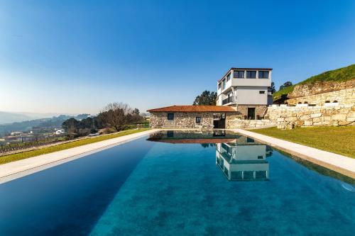 a pool of blue water in front of a building at Quinta de Casal do Bairro - Casa Grande in Guimarães