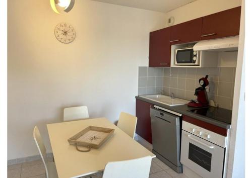 une cuisine avec une table et une table ainsi qu'une horloge murale dans l'établissement SP020-B002 Appartement 2 pièces Saint Pierre la Mer, à Saint Pierre La Mer