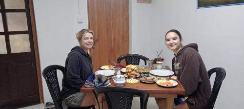 two people sitting at a table with food at sasru holiday home in Nuwara Eliya
