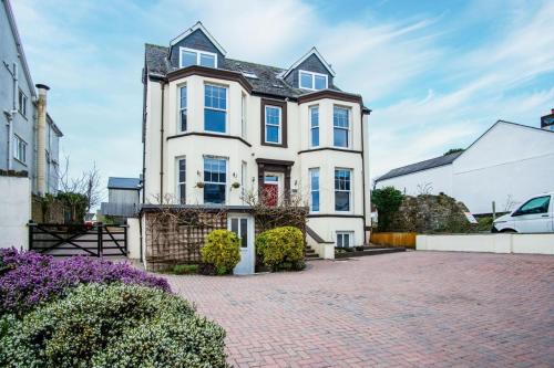 a white house with blue windows on a brick driveway at The Lanterns - 9 Bedroom - Sleeps 17 - Saundersfoot Village Centre in Saundersfoot