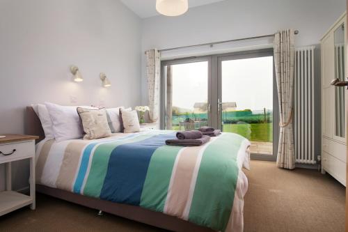 a bedroom with a bed and a large window at Sloopside Apartment in the centre of Bantham with sea views in Bantham