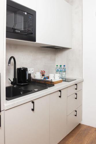 a white kitchen with a sink and a microwave at Lipowa32 Apartamenty in Hrubieszów