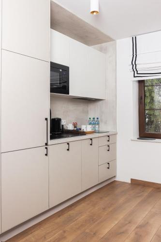 a white kitchen with white cabinets and a wooden floor at Lipowa32 Apartamenty in Hrubieszów