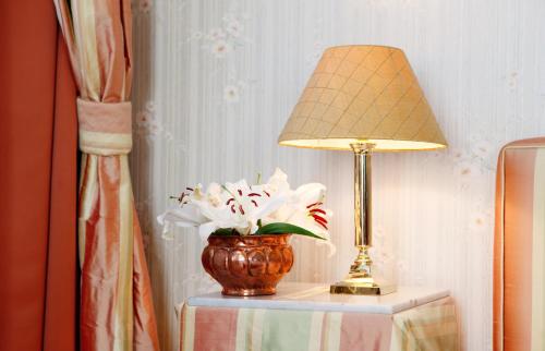 a lamp and a vase of flowers on a table at Hotel Goldener Anker in Bayreuth