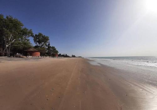 an empty beach with trees and the ocean at L'Eden in Palmarin