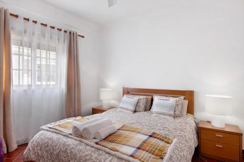 a bedroom with a bed with two lamps and a window at Casa Oliveira in Conceição