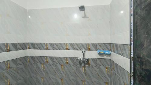 a shower in a bathroom with tiles on the wall at Aashirwad Residency Inn in Gaya
