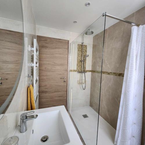 La salle de bains est pourvue d'une douche et d'un lavabo blanc. dans l'établissement Victoria - Dr Picaud - 3 Pieces avec climatisation - 5 min des Plages, à Cannes