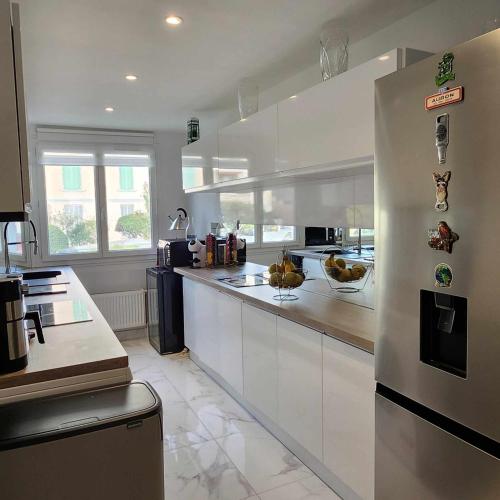 une cuisine avec des armoires blanches et un réfrigérateur en acier inoxydable dans l'établissement Victoria - Dr Picaud - 3 Pieces avec climatisation - 5 min des Plages, à Cannes