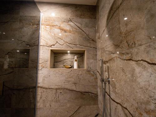 a bathroom with a shower with a stone wall at Hardriggs Bank Cottage in Kendal