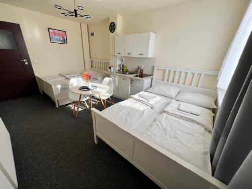 a bedroom with a bed and a table and a kitchen at Noclegi AirportPark in Pyrzowice
