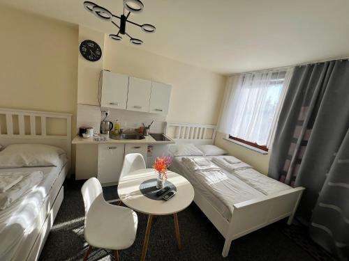 a room with two beds and a table and a kitchen at Noclegi AirportPark in Pyrzowice