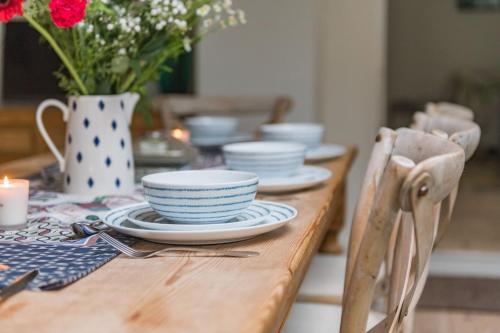 a wooden table with plates and a vase with flowers at Warwick Villa in Walmer