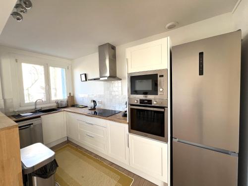 une cuisine avec des armoires blanches et un réfrigérateur en acier inoxydable dans l'établissement Le Notre Dame maison spacieuse avec jardin, à Calais