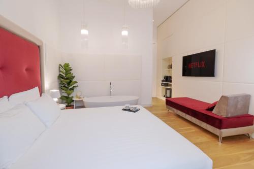 a white bedroom with a large bed and a red bench at Domus Aurea Luxury Suites in Rome