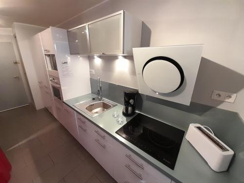 - une petite cuisine avec un évier et un miroir dans l'établissement Appartement Village Naturiste Intense, au Cap d'Agde