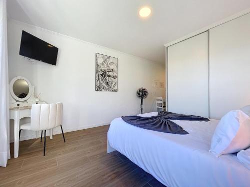 a white bedroom with a bed and a desk at Madeiran Sweet Home in Funchal