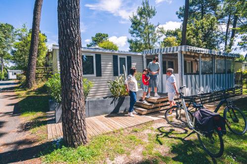 une famille debout à l'extérieur d'une petite maison dans l'établissement Bonne Anse Plage 409 Mobile home 3 chambres 7 personnes, aux Mathes