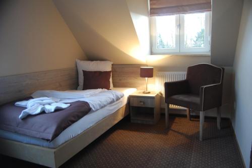 a small bedroom with a bed and a chair at Hotel Piast przy Zamku in Malbork
