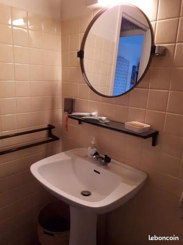 une salle de bain avec un lavabo blanc et un miroir dans l'établissement appartement T3 tout confort, à Cabourg