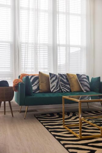 a living room with a green couch and a table at Two Story Penthouse, 2 Bedrooms with 2 and a half bathrooms, 2 Balconies, Skyline View, Pool in Richmond